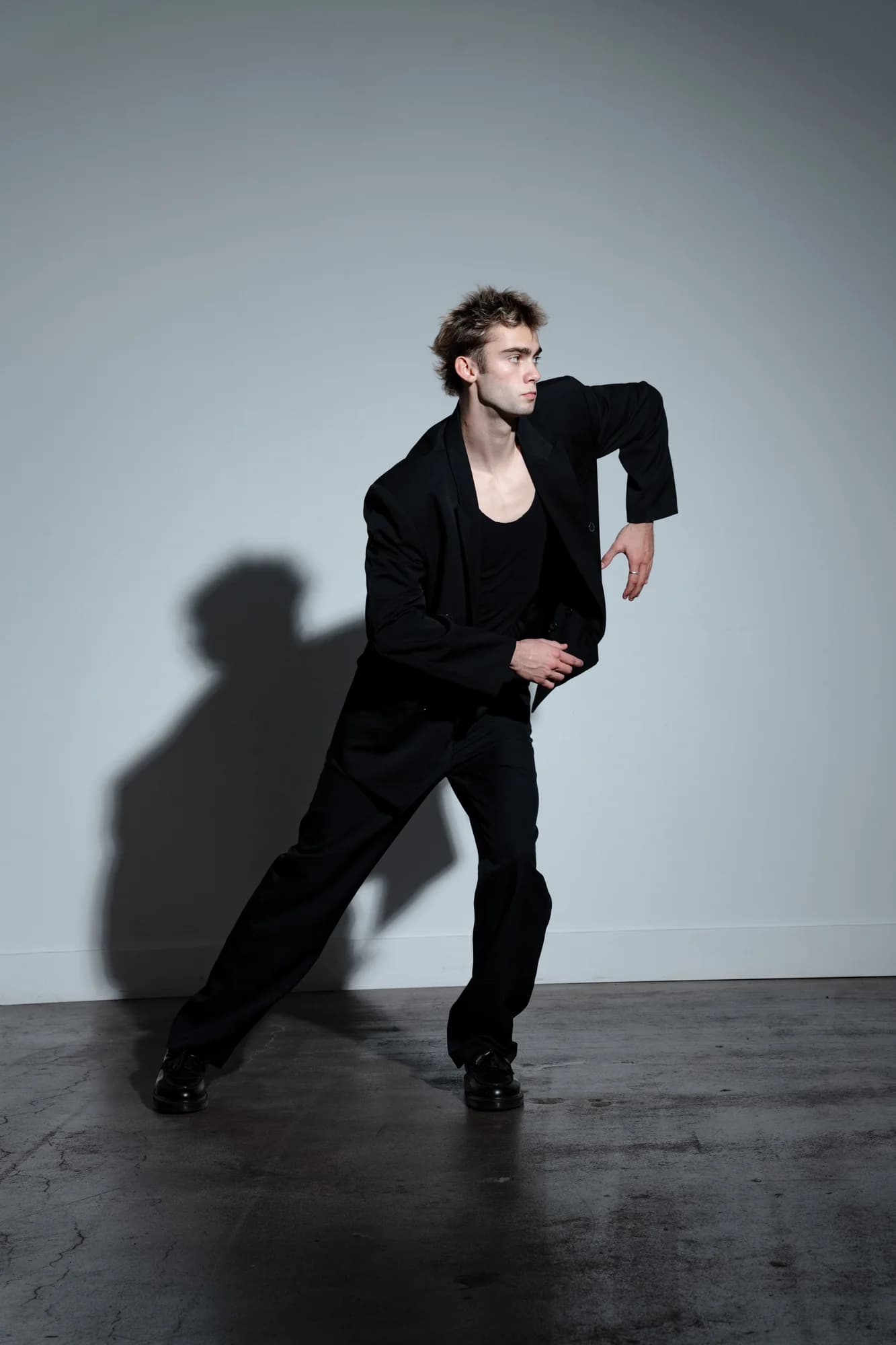 Jeffrey holding an angular standing pose in a black suit