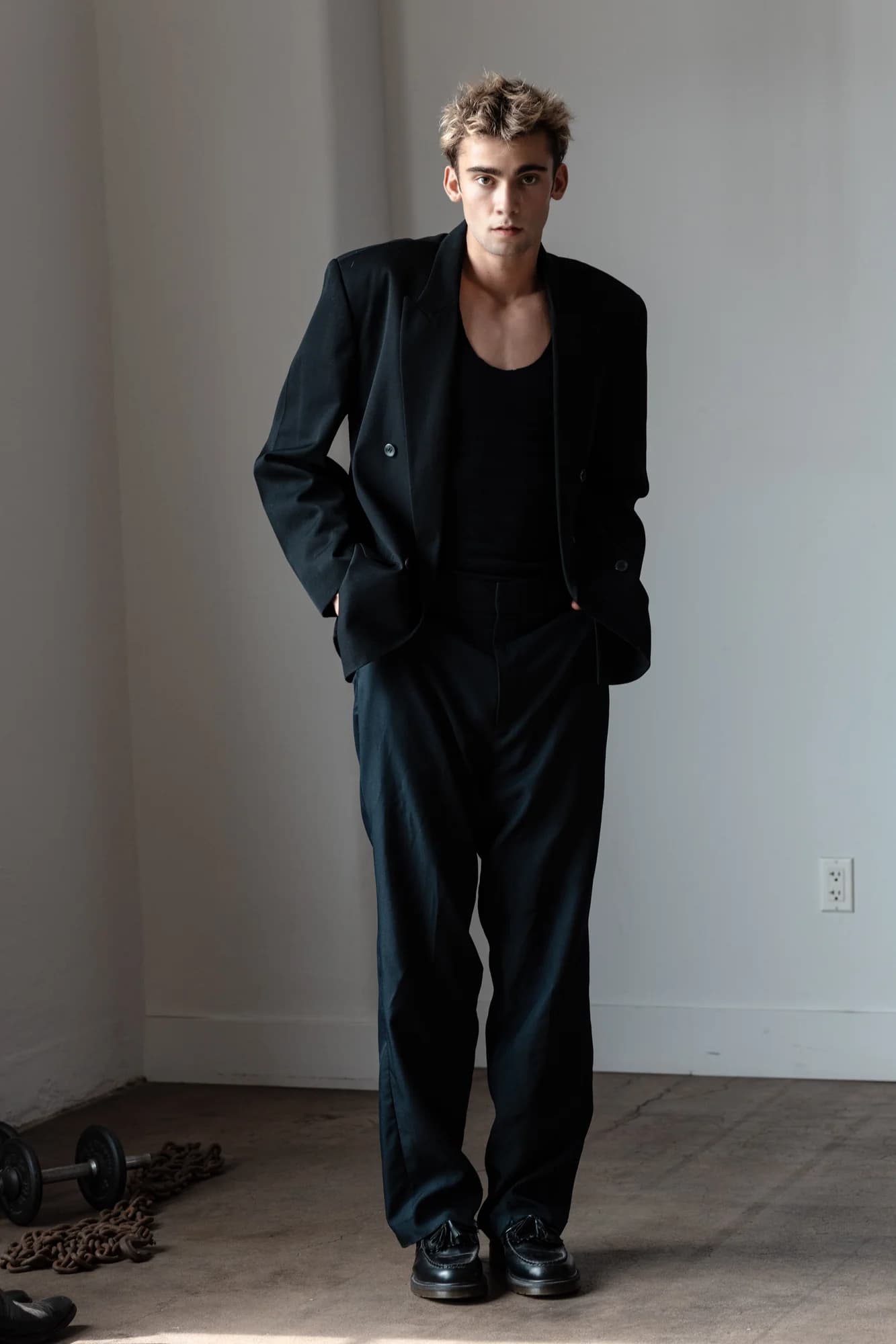 Jeffrey standing in a black suit in hard studio light